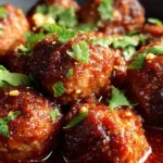Slow Cooker Sweet Spicy Meatballs cooking in a pot with rich sauce.