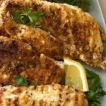 Plate of yogurt marinated chicken garnished with herbs.