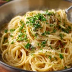 Delicious cheesy garlic pasta served in a bowl with herbs on top.