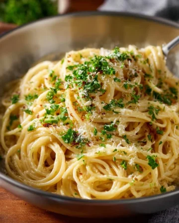 Delicious cheesy garlic pasta served in a bowl with herbs on top.