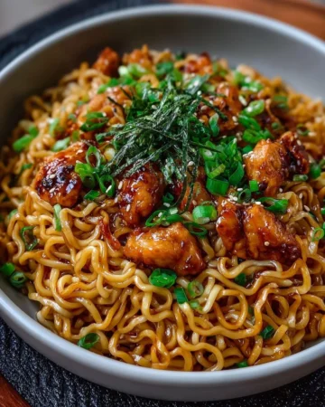 Delicious sticky garlic chicken noodles garnished with herbs and vegetables.