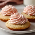 Sugar cookie buttercream frosting spread on freshly baked cookies.