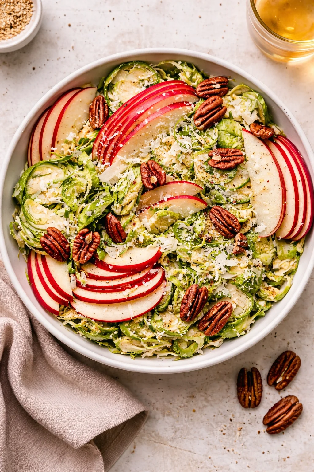 Brussels sprout apple salad with nuts and dressing served in a bowl