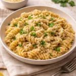 Crockpot garlic parmesan chicken pasta in a bowl with herbs and cheese.