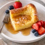 Delicious homemade German pancakes served with syrup and powdered sugar