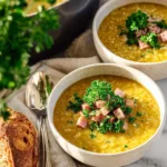 Bowl of split pea and ham soup garnished with herbs