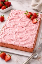 Deliciously moist strawberry sheet cake topped with fresh strawberries and frosting