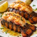 Delicious broiled lobster tail served on a plate with lemon and herbs