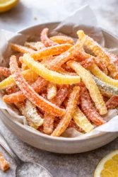 Homemade candied orange peel slices on a plate.