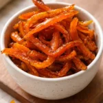 A bowl of homemade candied orange peels garnished with sugar