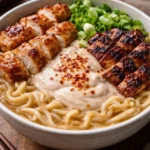 Bowl of creamy ramen chicken dish topped with herbs and spices