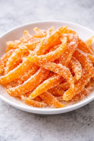 Bowl of homemade candied orange peels garnished with mint