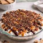 Delicious Turtle Cheesecake Dip topped with chocolate and nuts in a bowl