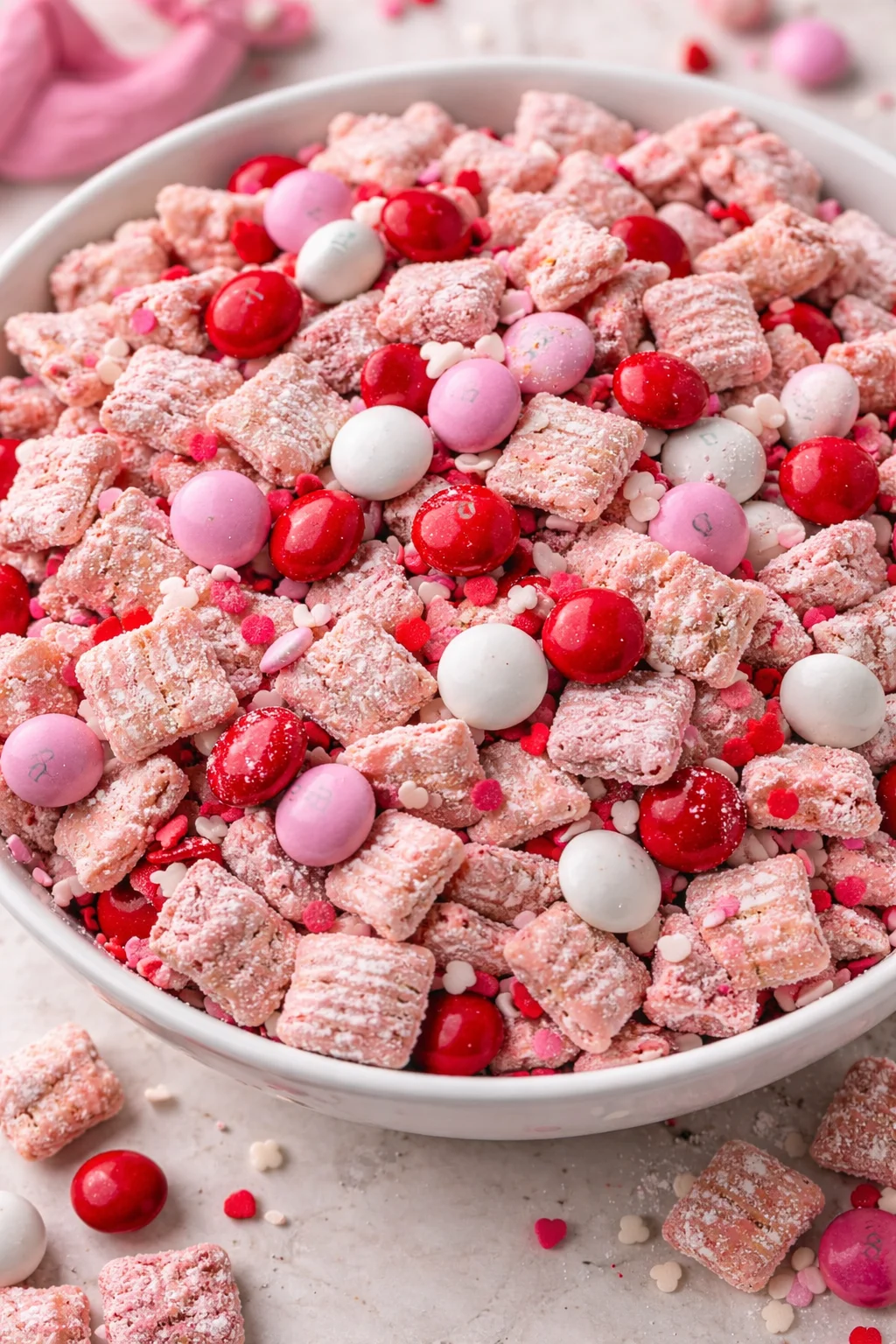 Valentine's Day themed Muddy Buddies snack mix in a heart-shaped bowl.