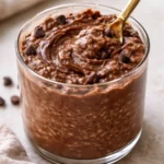 Bowl of brownie batter overnight oats topped with chocolate and nuts