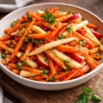 Fresh Carrot Apple Salad with nuts and dressing in a bowl