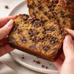 Slice of chocolate chip banana bread on a wooden table