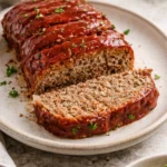 Delicious classic meatloaf sliced and served on a plate with mashed potatoes.