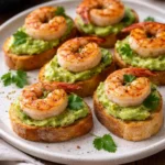 Garlic shrimp crostini topped with avocado on a platter