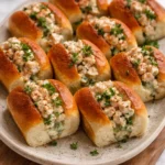 Mini shrimp rolls served on a platter, garnished with herbs.