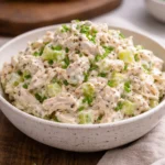 Bowl of simple chicken salad with fresh vegetables and dressing