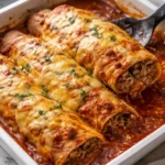 Ground beef enchiladas topped with cheese and sauce, ready to serve.