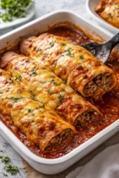 Ground beef enchiladas topped with cheese and sauce, ready to serve.