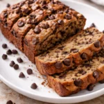 Slice of healthier chocolate chip banana bread on a wooden cutting board