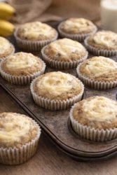 Freshly baked moist banana cream cheese muffins on a cooling rack