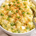 A bowl of creamy Southern Potato Salad garnished with herbs