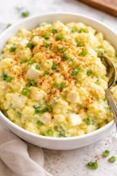 A bowl of creamy Southern Potato Salad garnished with herbs