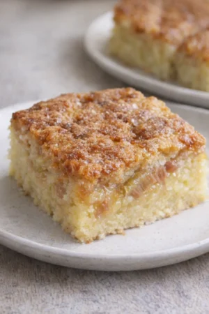 Delicious vanilla rhubarb custard bars on a plate, garnished with fresh rhubarb.
