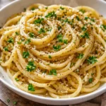 Plate of garlic butter pasta with fresh herbs and Parmesan cheese