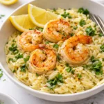 Dish of zesty lemon garlic shrimp over orzo pasta garnished with parsley.