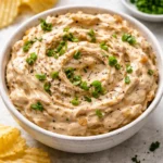 Delicious brandied caramelized onion dip served in a bowl with crispy chips