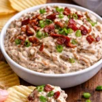 Creamy caramelized onion dip served in a bowl with chips and fresh veggies