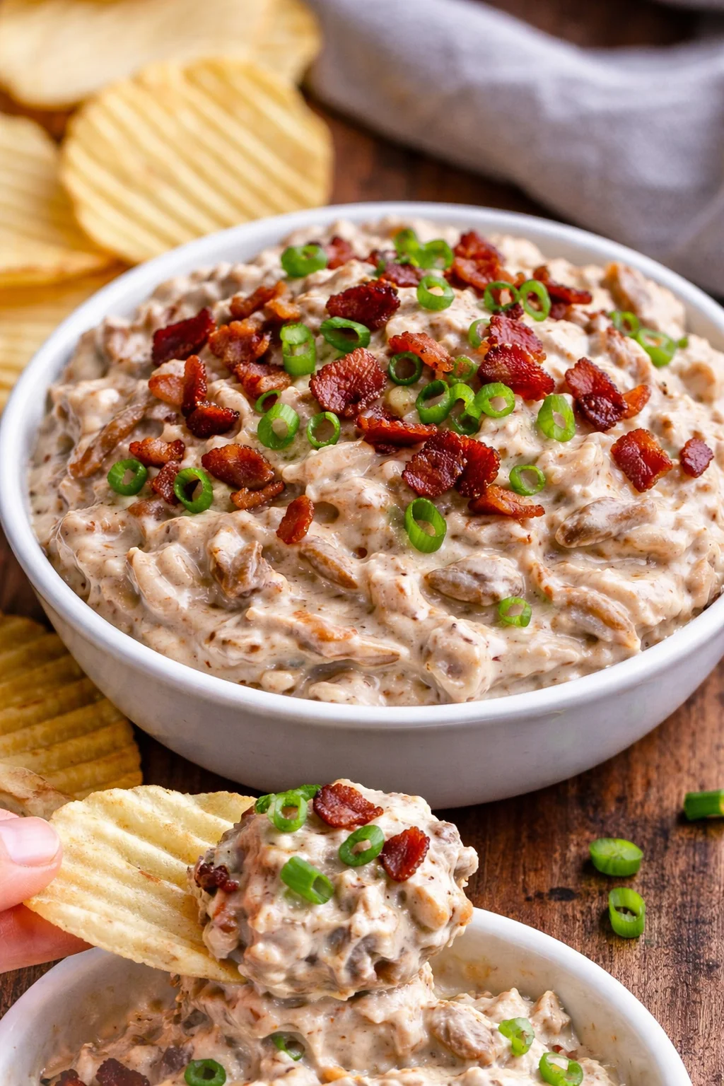 Creamy caramelized onion dip served in a bowl with chips and fresh veggies